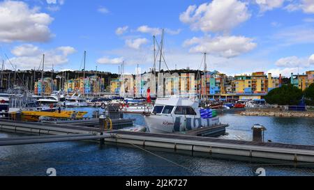 Yachts, excursion and pleasure boats docked at Albufeira marina, colorful apartment buildings, restaurants, bars and shops in the background. Algarve, Stock Photo