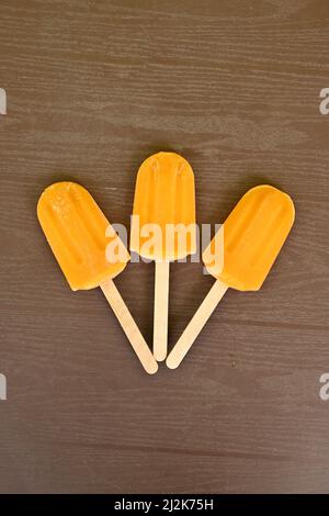 closeup the bunch orange color and flavor stick ice cream over out of focus brown background. Stock Photo