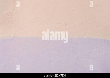 The colored wall is two colors: light warm cream or peach and lilac bright abstract paint background design. Stock Photo