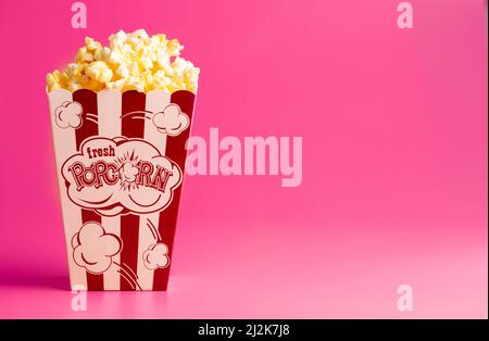 Red and White Striped Popcorn Bucket Isolated on a Pink Background Stock Photo