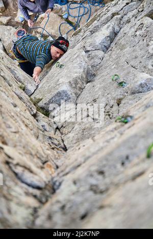 Man in harness climbing rock in highlands Stock Photo