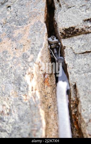 Metal climbing cam in rock in highlands Stock Photo