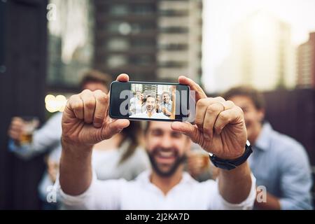 We have to take a photo together. Portrait of a group of cheerful young work colleagues taking a self portrait together outside during the day. Stock Photo