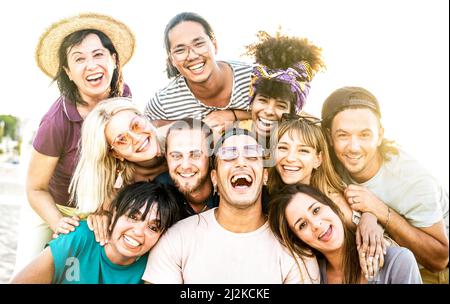 Mixed age range friends taking selfie at beach festival - Happy life style and summer vacation concept on trendy multicultural people having fun day Stock Photo
