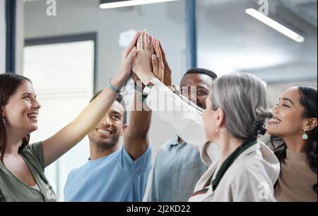 We promise to always support each other. Shot of a group of businesspeople giving each other a high five in an office. Stock Photo