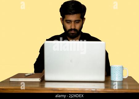 Work From Home. A man working on laptop. A coffee mug and diary kept on side. selective focus. Stock Photo