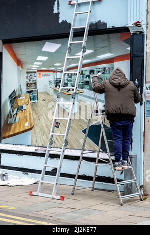 Kingston Upon Thames London UK, April 01 2022, Painter Painting The Outside Of A Shop Front Standing On A Step Ladder Stock Photo