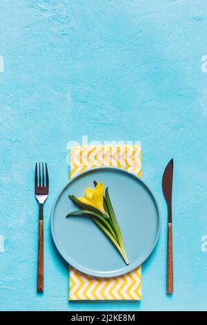 Spring table layout with plate and tableware on turquoise blue background. Spring Holidays background. Top view, flat lay, copy space. Stock Photo
