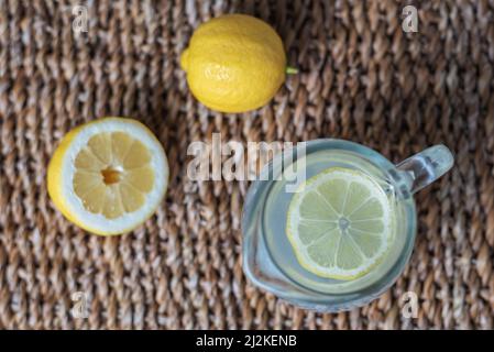 Pitcher of lemonade with a slice of lemon on top, accompanied by half a lemon and another whole. Aerial view. Stock Photo
