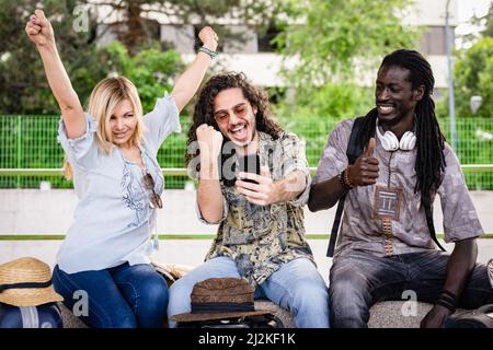 three people from diverse ethnies and culture travelling with train, happy friends using smartphone and technology for travelling around the world Stock Photo
