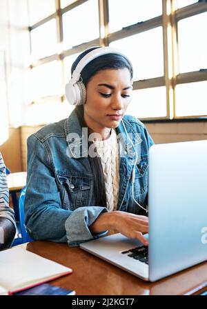 Shes a diligent student. Cropped shot of an attractive young university student working on her laptop while sitting in class. Stock Photo