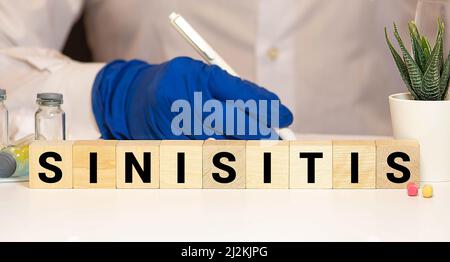SINUSITIS the word on wooden cubes, cubes stand on a reflective white surface, on cubes - a stethoscope. Medicine concept Stock Photo