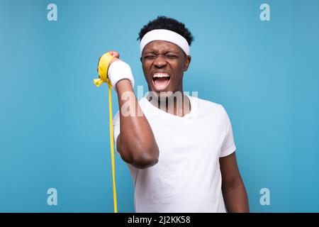 African american sportsman doing sport exercise. Studio shot on blue wall Stock Photo