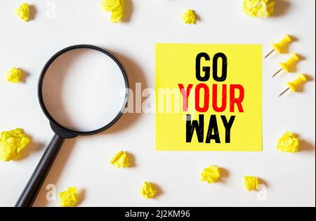 yellow sticker inscription Go your own way attached blue magnet white fridge. close-up Stock Photo