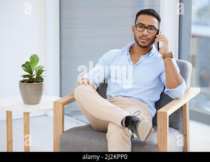 Making connections is as easy as picking up your phone. Shot of a young businessman using a smartphone at work. Stock Photo