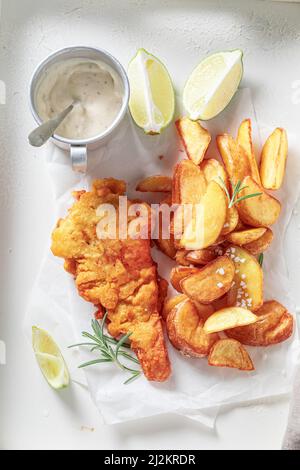 Grilled cod and potatoes served with lime and salt. Classic fish and chips served in paper. Stock Photo