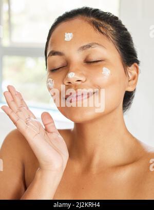 You dont have to be perfect to be beautiful. Shot of young woman using with facial moisturiser at home. Stock Photo
