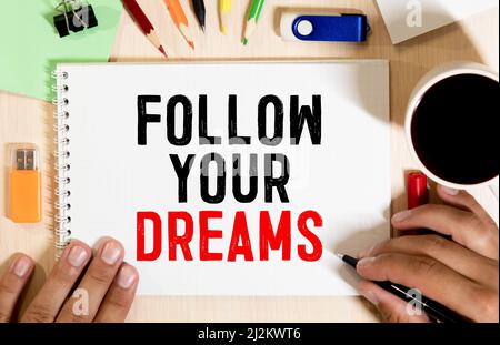 Retro instagram style image of a male hand writing motivational message Follow your dreams on virtual board. Stock Photo