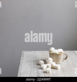 Cup with refined sugar in pieces scattered on the table Stock Photo