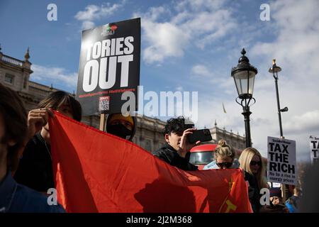 London, UK. 02nd Apr, 2022. Teenagers are seen holding their phones to film the rally and holds a red communist flag and placard during the rally. People's Assembly called for a national demonstration against the Conservative government not being able to tackle the increase in cost of living in the UK. The cost of living in the UK soars as food and energy prices increase partly due to the ongoing Russia-Ukraine war. Credit: SOPA Images Limited/Alamy Live News Stock Photo