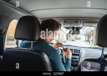 One man adult caucasian male drinking alcohol from flask while drive a car drunk back view copy space alcoholism and alcohol abuse concept intoxicated Stock Photo