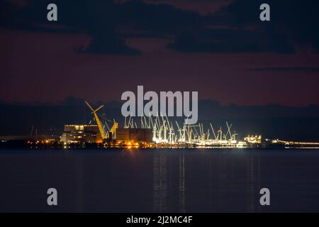 Burnham on Sea, Somerset, UK.  2nd April 2022.  UK Weather.  View along the coast from Burnham on Sea on the severn estuary in Somerset of the construction site of Hinkley Point C nuclear power station which is brightly lit up at dusk.  Picture Credit: Graham Hunt/Alamy Live News Stock Photo