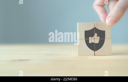 Quality warranty concept.  Man's hand puts the wooden cubes with quality warranty icon on wooden cubes with grey background. Used for banner and adver Stock Photo