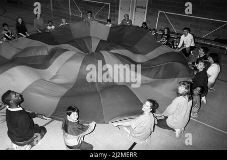 Playaway... pictured are some of the 20 children from all over Kirklees who enjoyed a play day at Mount Pleasant Sports Centre, Lockwood, organised by Helen Robinson, recreation officer for disabilities. Voluntary helpers pitched in to help the children, aged between eight to 15, take part in activities such as this parachute game, football and volleyball. 30th May 1991. Stock Photo