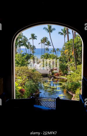 A framed archway garden view looking over the koi pond to palm trees and the Pacific Ocean at the The Fairmont Kea Lani Maui Resort, Wailea, Maui, Haw Stock Photo