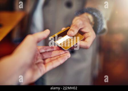 Ill put it on my card. Cropped shot of an unrecognizable young man handing over a credit card in a shop. Stock Photo