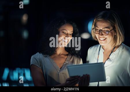 Smart apps made their night productive. Shot of two colleagues using a digital tablet together during a late night at work. Stock Photo