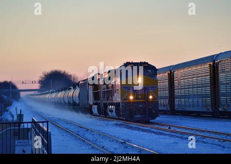 La Fox, Illinois, USA. Just as the sun was setting, an eastbound Union Pacific freight train headed by two locomotives passes another stopped train. Stock Photo