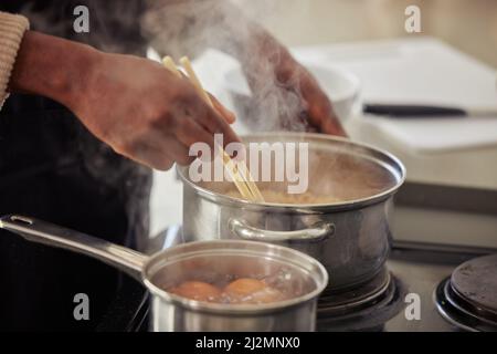 Cooking up a storm. Cropped shot of an unrecognizable man cooking on his stove in the kitchen at home. Stock Photo