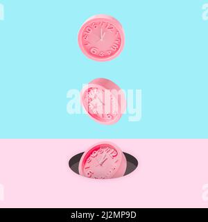 Pastel pink wall clocks on blue backdrop falling down. Time concept. Minimal composition. Stock Photo