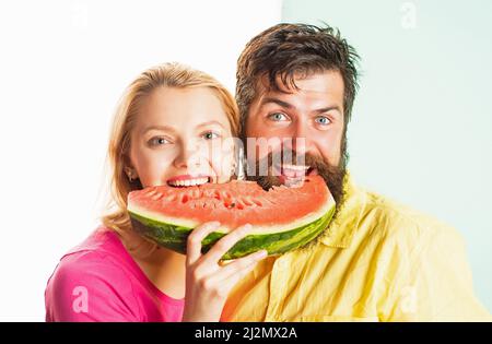 Happy face closeup of couple enjoying watermelon. Cheerful couple holding slices of watermelon. Funny face. Stock Photo