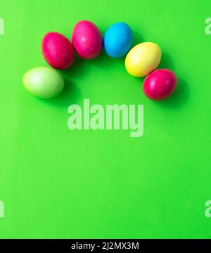 Multi-colored eggs are laid out in an arch on a green background. Easter rainbow. Postcard. Congratulation. Invitation. Stock Photo