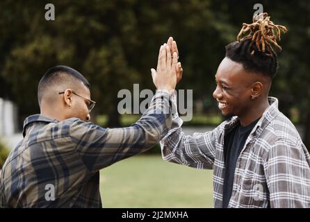 Put it up top. Shot of two young men giving each other a high five on campus. Stock Photo