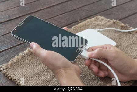 woman are connected charging cable to the smartphone by external battery. Stock Photo
