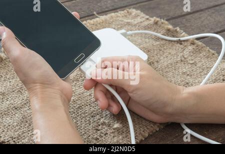 woman are connected charging cable to the smartphone by external battery. Stock Photo