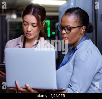 Running diagnostics. Cropped shot of two attractive young female computer programmers working together in a server room. Stock Photo