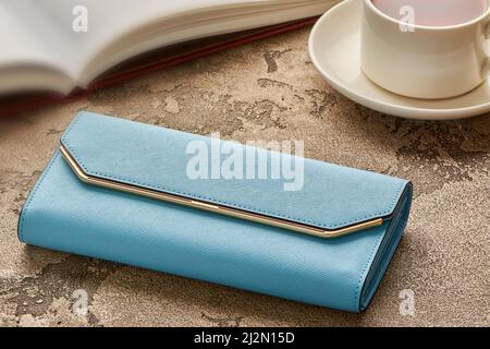 A blue woman's purse lies on a concrete background with a cup of coffee and a book Stock Photo
