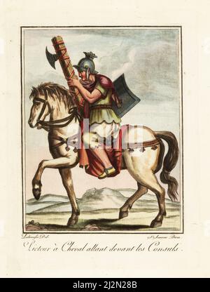 Lictor riding in front of consuls, ancient Rome. In galea helmet, tunic, sagulum gregale or short trousers, sandals, with fasces and scutum shield. Licteur a Cheval allant devant les Consuls. Handcoloured copperplate drawn and engraved by L. Labrousse, artist of Bordeaux, under the direction of Jacques Grasset de Saint-Sauveur from his L’antique Rome, ou description historique et pittoresque, Ancient Rome, or historical and picturesque description, Chez Deroy, Paris, 1796. Stock Photo