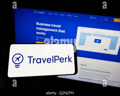 Person holding cellphone with logo of Spanish software company TravelPerk SLU on screen in front of business webpage. Focus on phone display. Stock Photo
