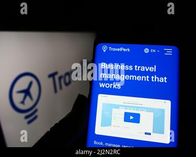 Person holding smartphone with webpage of Spanish software company TravelPerk S.L.U on screen in front of logo. Focus on center of phone display. Stock Photo