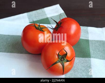 Vibrant red tomatoes on a green and white kitchen towel Stock Photo