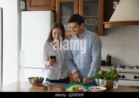 Happy young married couple cooking in home kitchen Stock Photo