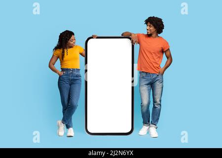 Curious african american couple looking at smartphone, mockup Stock Photo