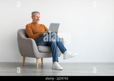 Confident smiling mature man using laptop at home Stock Photo