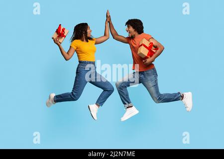 Happy man and woman with gift boxes giving high five Stock Photo