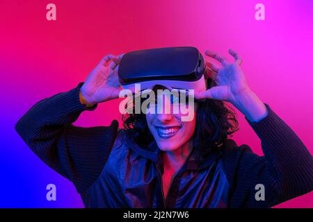 The young woman is using the virtual reality viewer. Portrait of modern smiling woman with trendy look and bright colors. Stock Photo